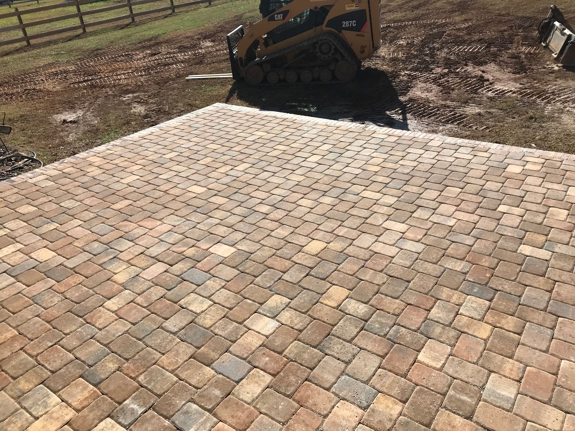 A bulldozer is sitting on top of a brick patio.