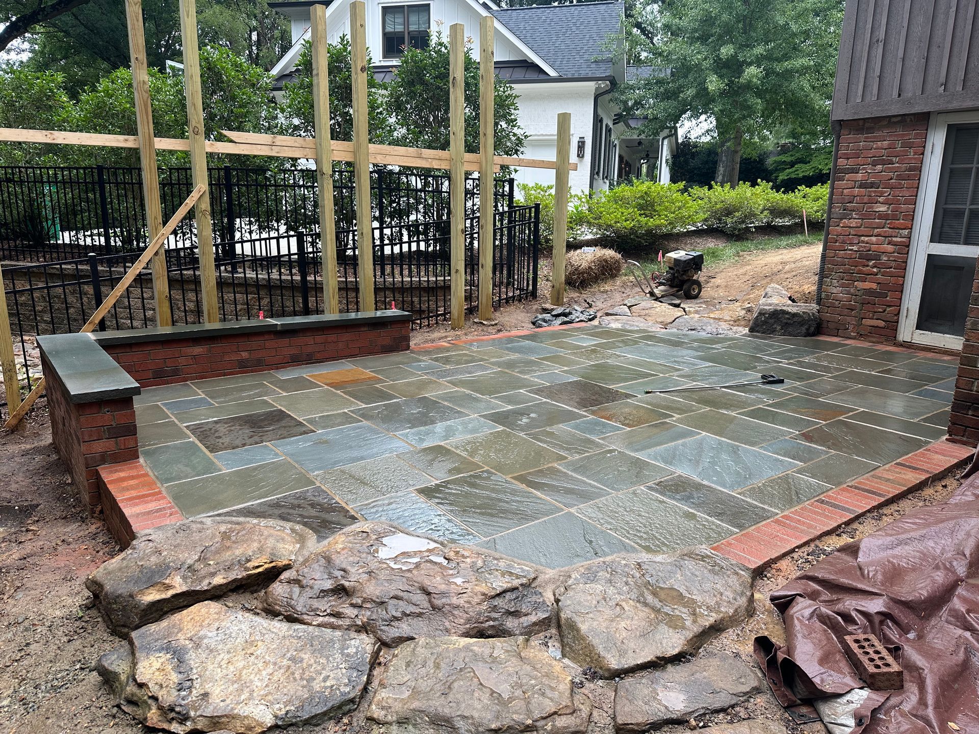 A stone patio is being built in the backyard of a house.