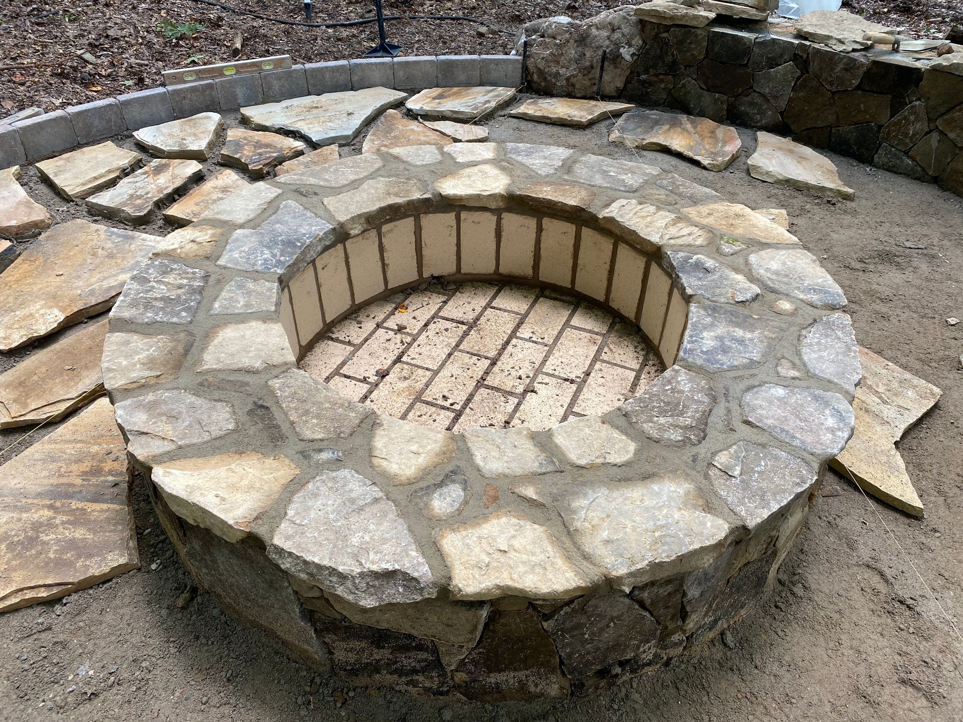 A stone fire pit is surrounded by rocks and sand.