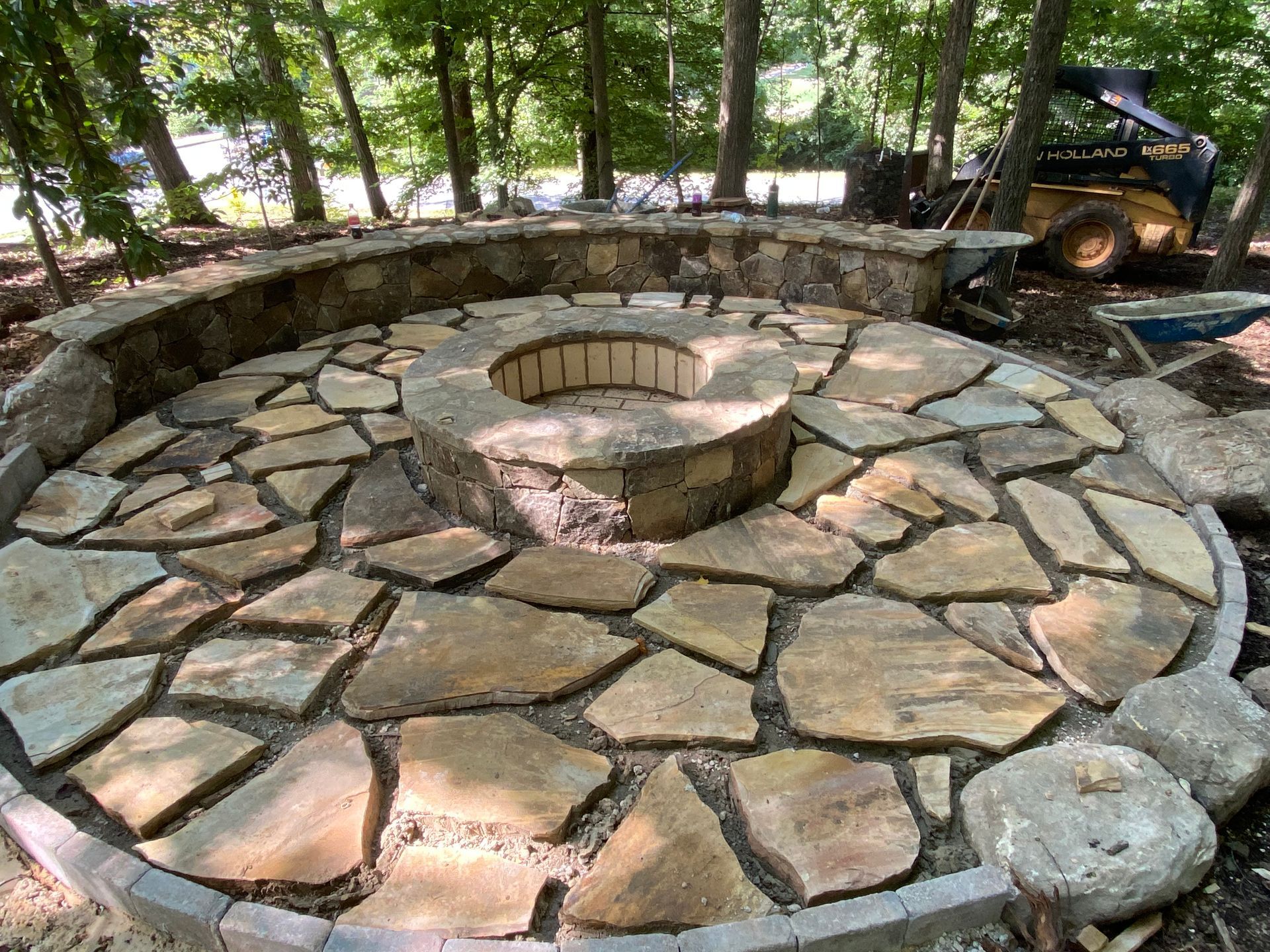 A fire pit is surrounded by a stone wall in the middle of a circle.