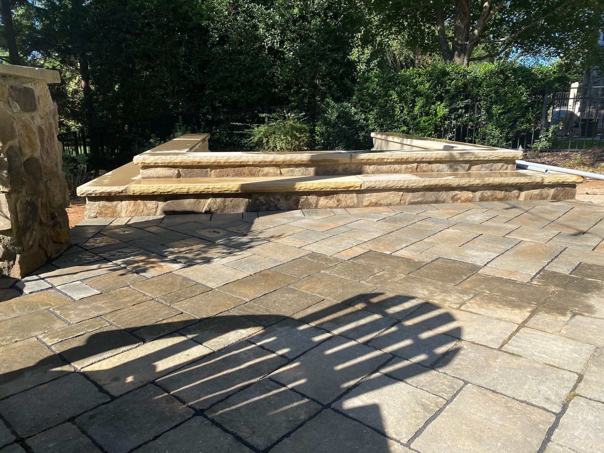 A shadow of a person is cast on a stone patio.