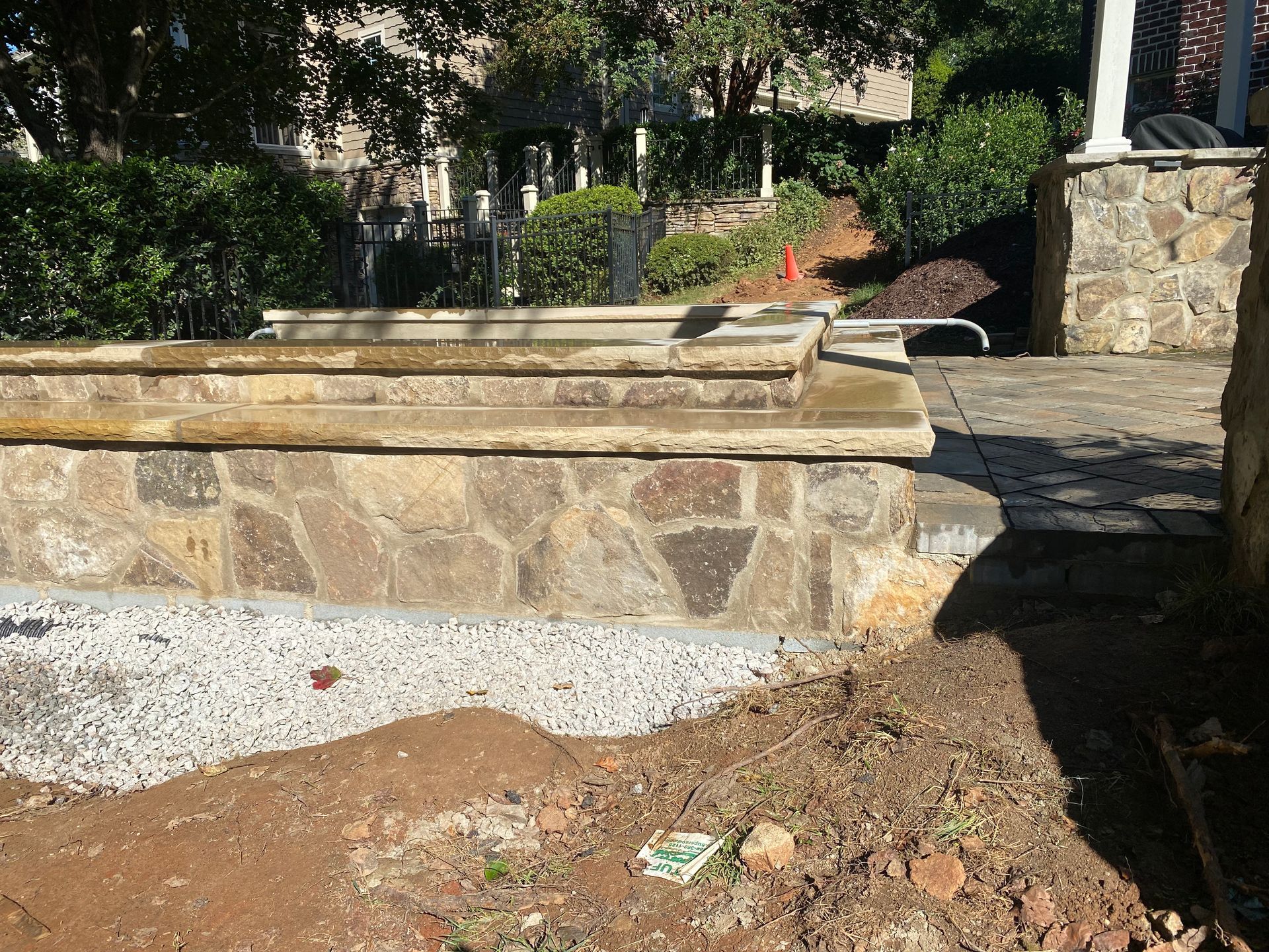 A stone wall is being built in a yard next to a tree.