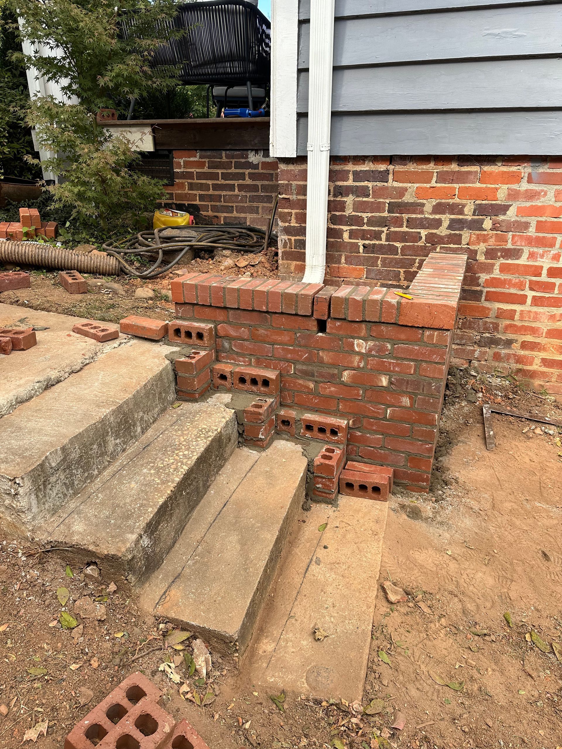 A brick wall with stairs and bricks in front of a house.