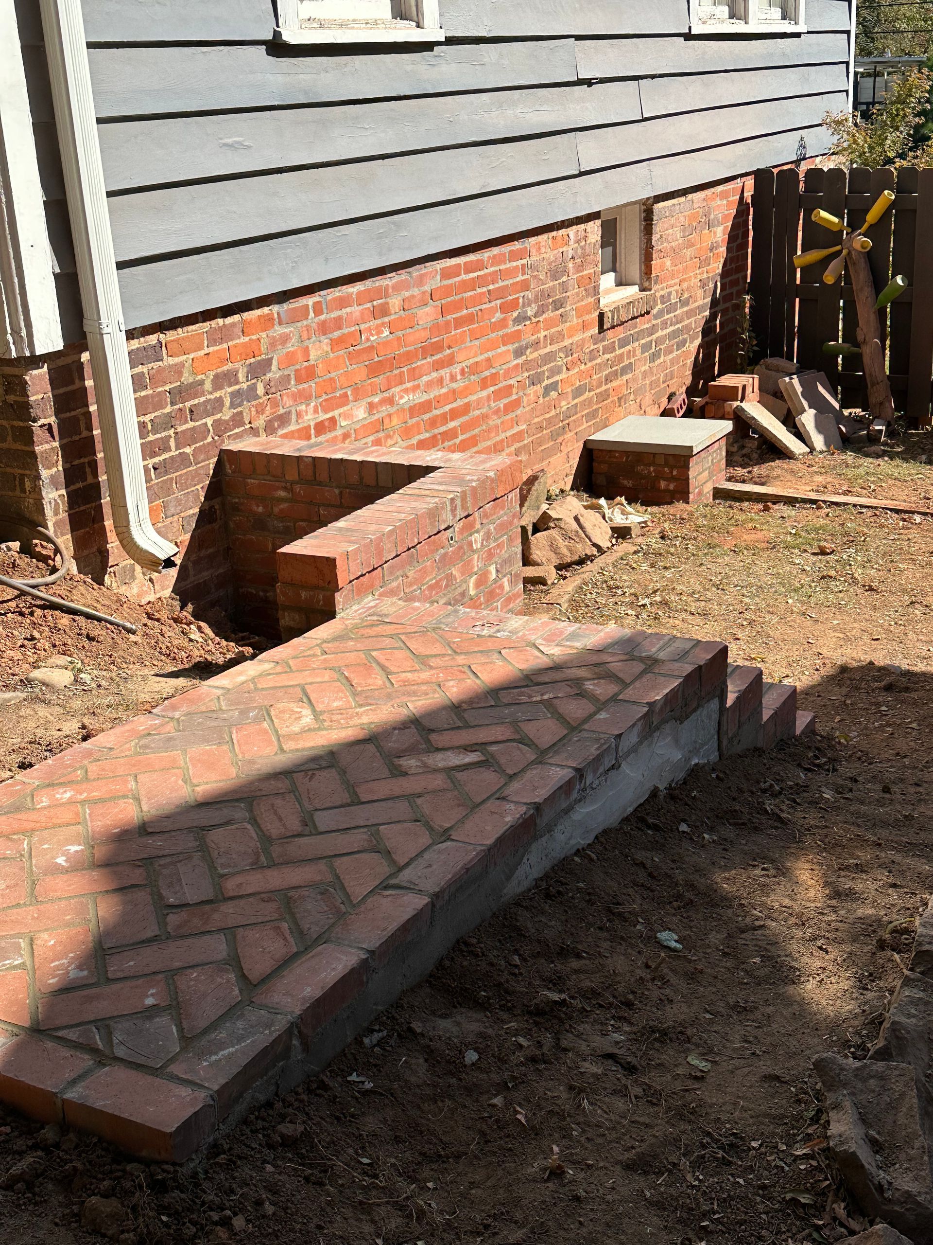 A brick walkway is being built in front of a brick house.