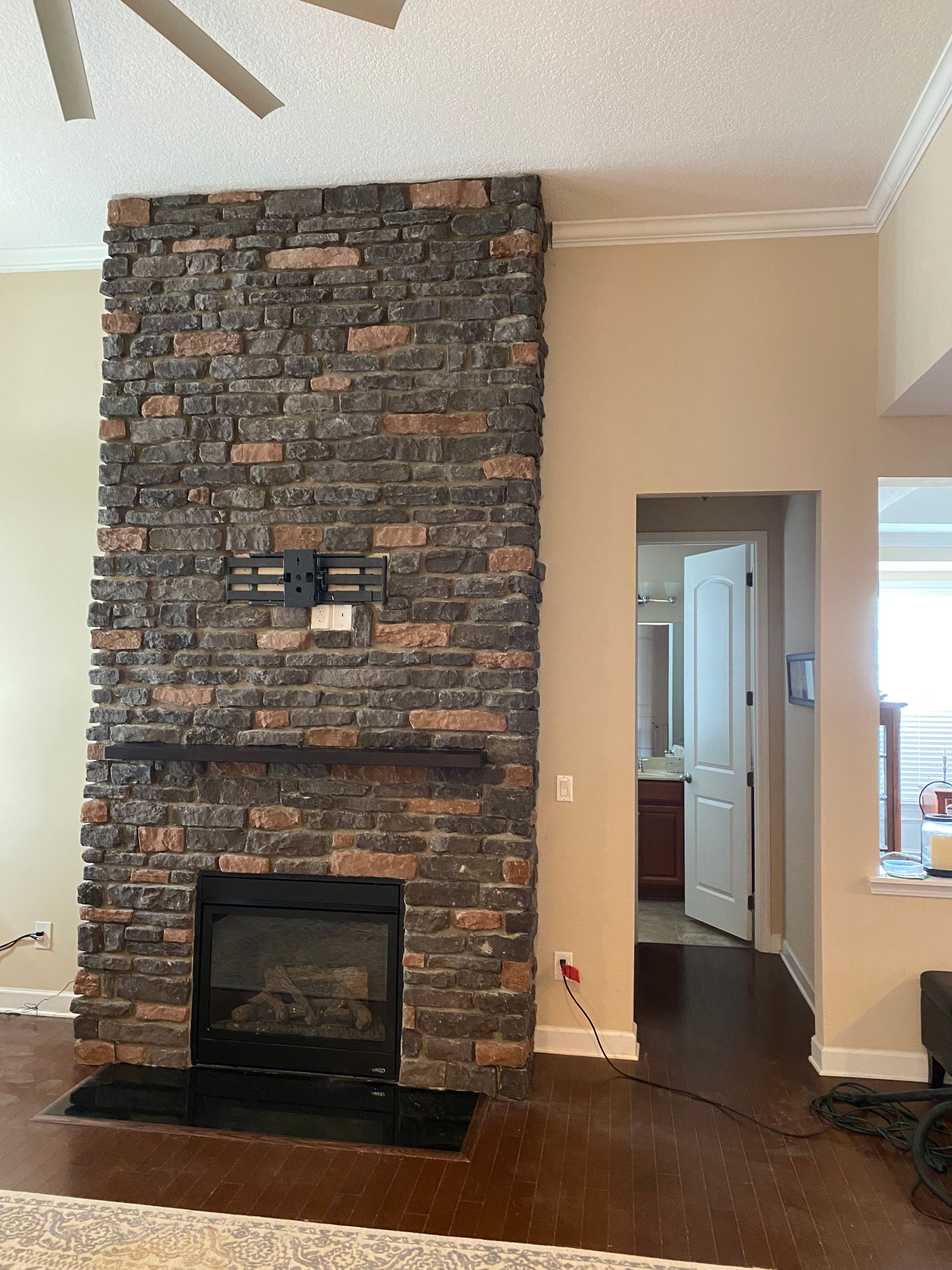 A living room with a brick fireplace and a ceiling fan