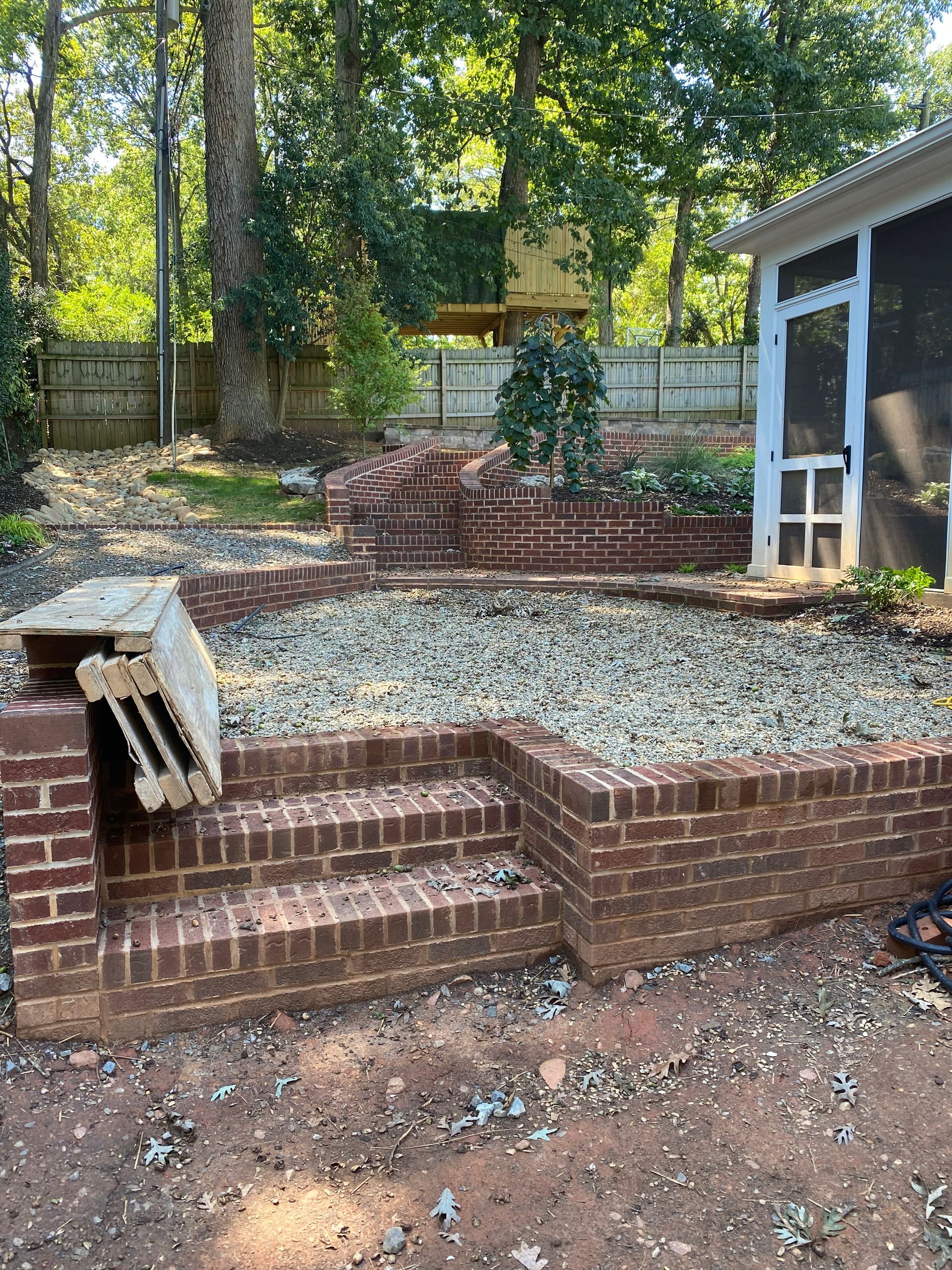 A brick patio with stairs leading up to a screened in porch.