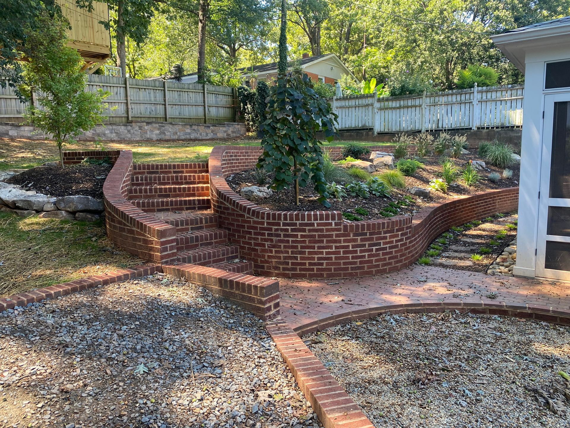 A brick walkway with stairs leading up to a screened in porch.