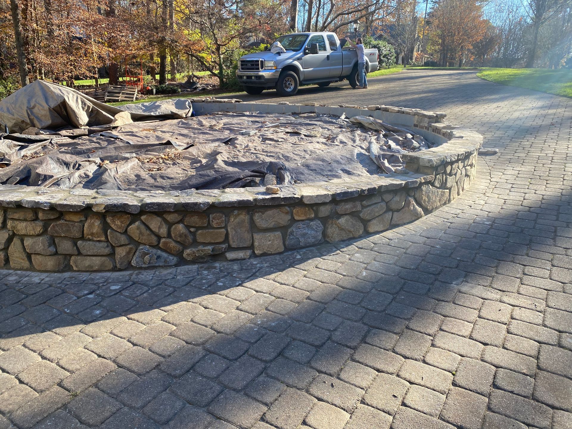 A truck is parked in a driveway next to a fire pit.