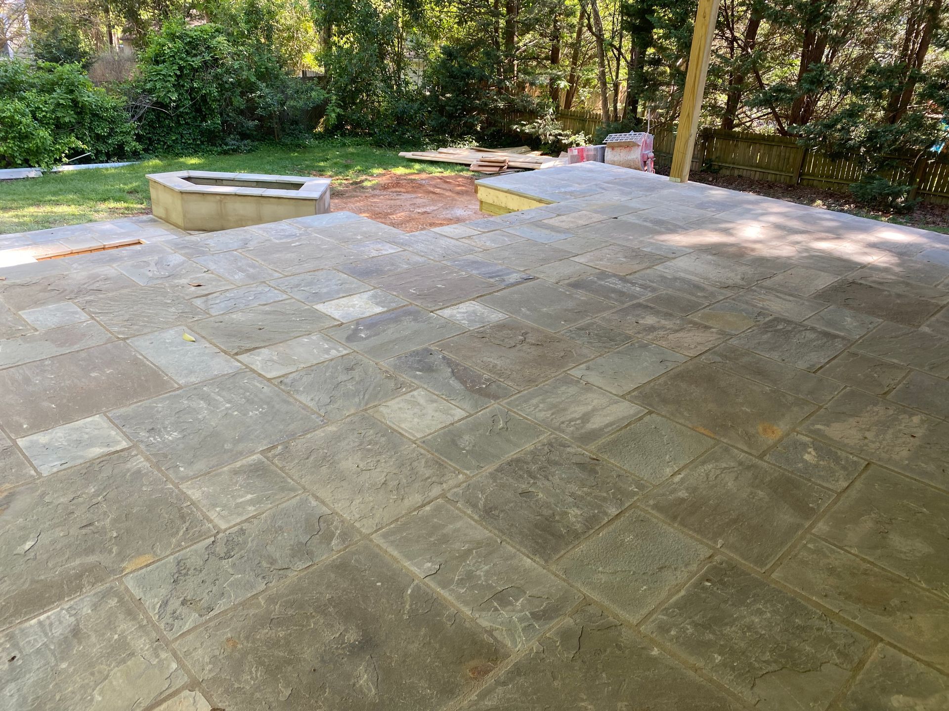 A patio with a fire pit and trees in the background
