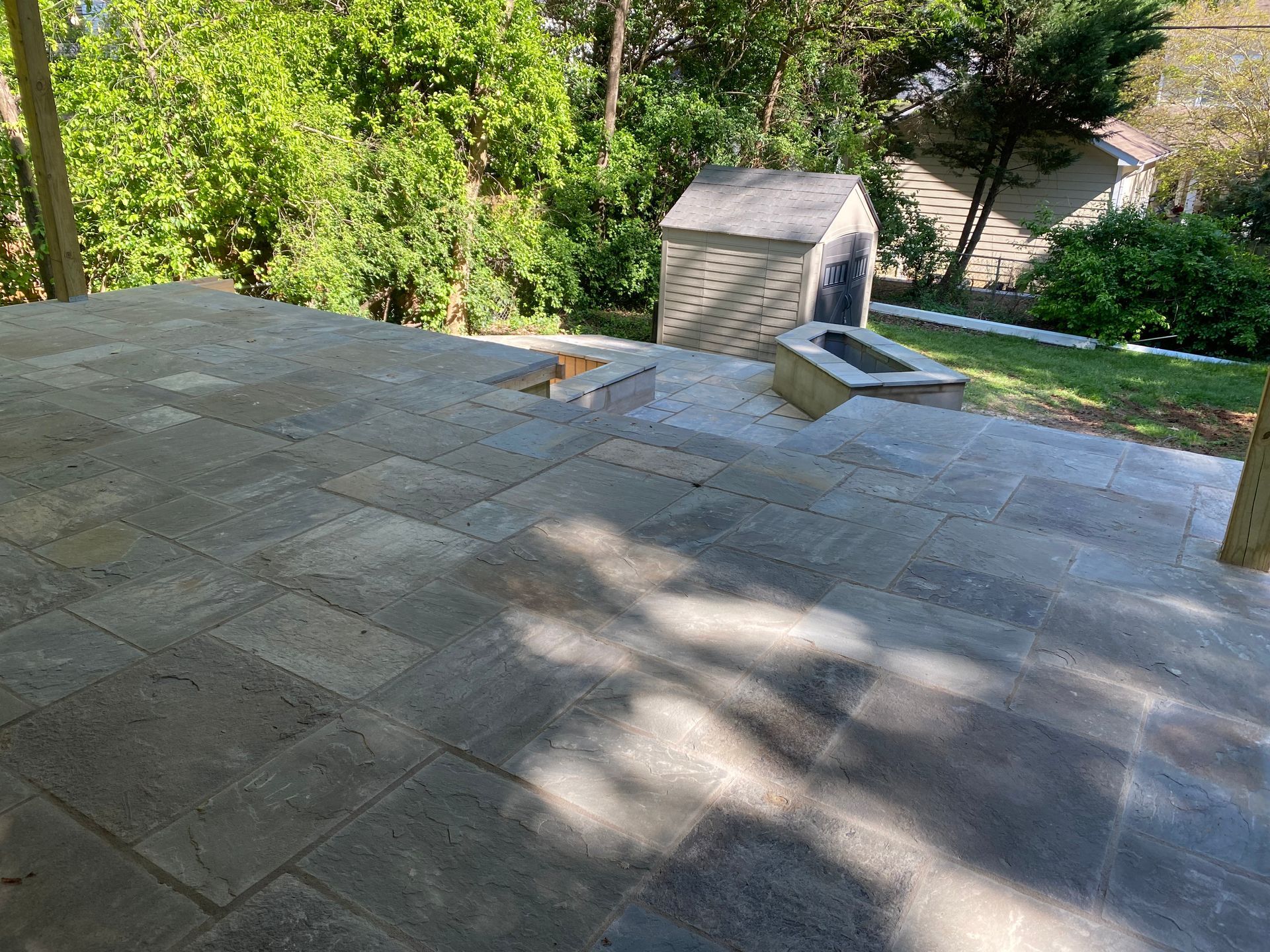 A patio with a fire pit and a shed in the background.