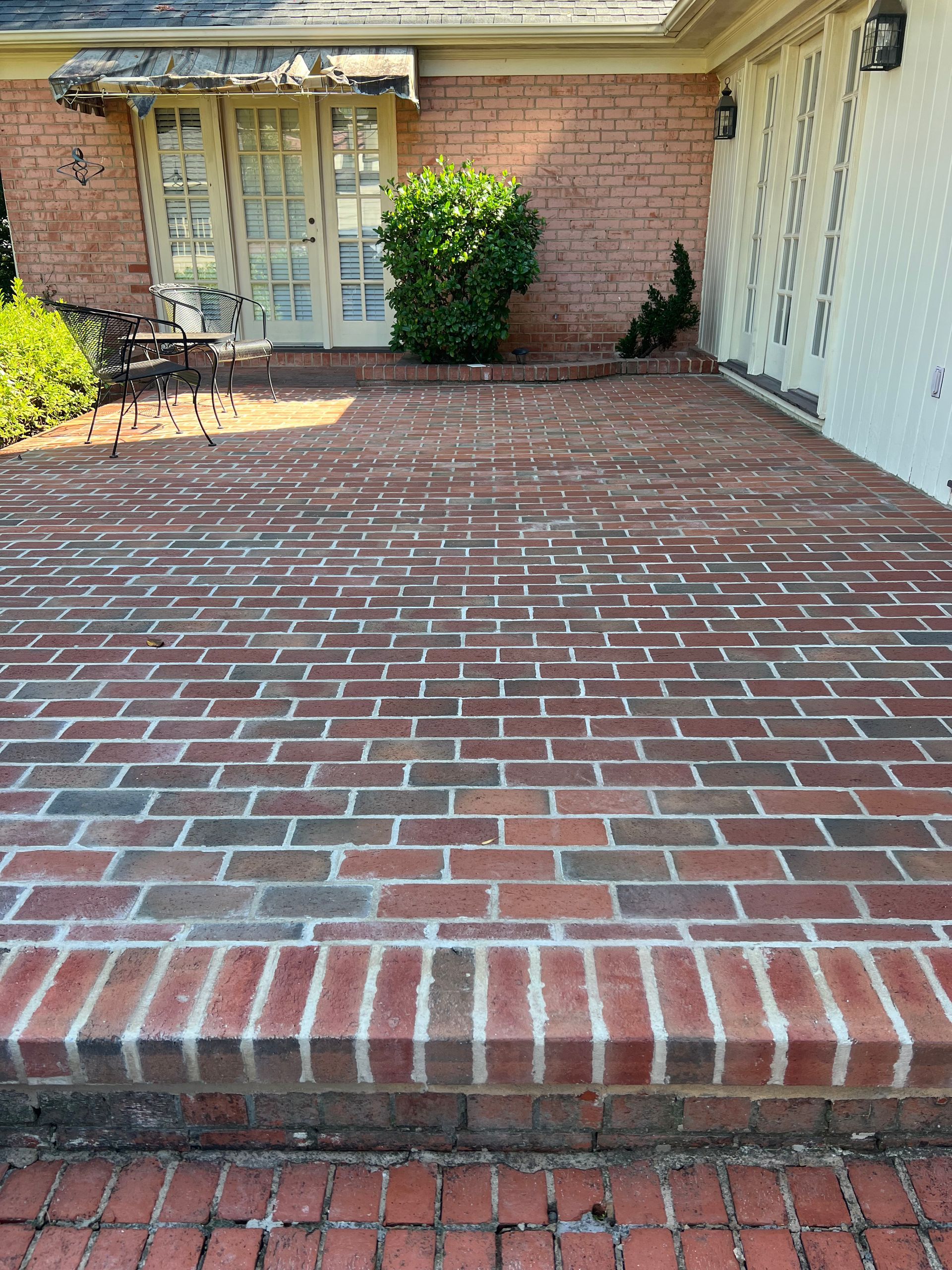 A brick patio in front of a house with a sliding glass door.