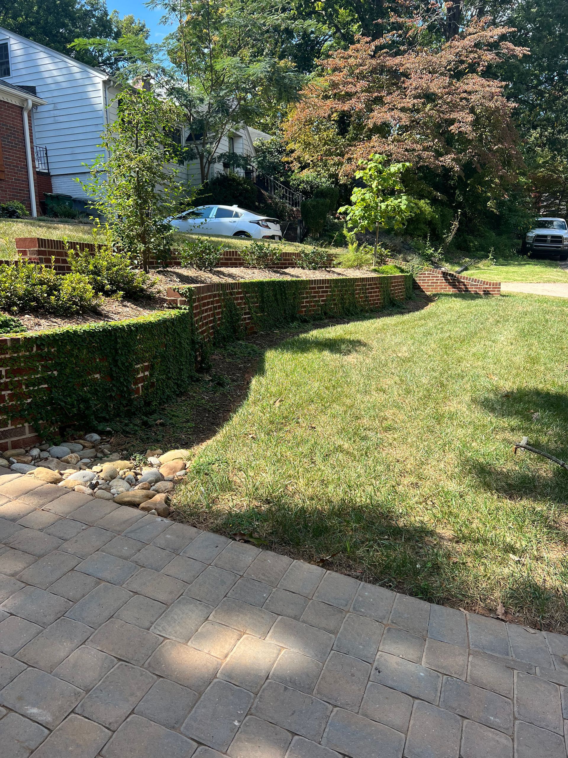 A car is parked in a driveway next to a lush green lawn.