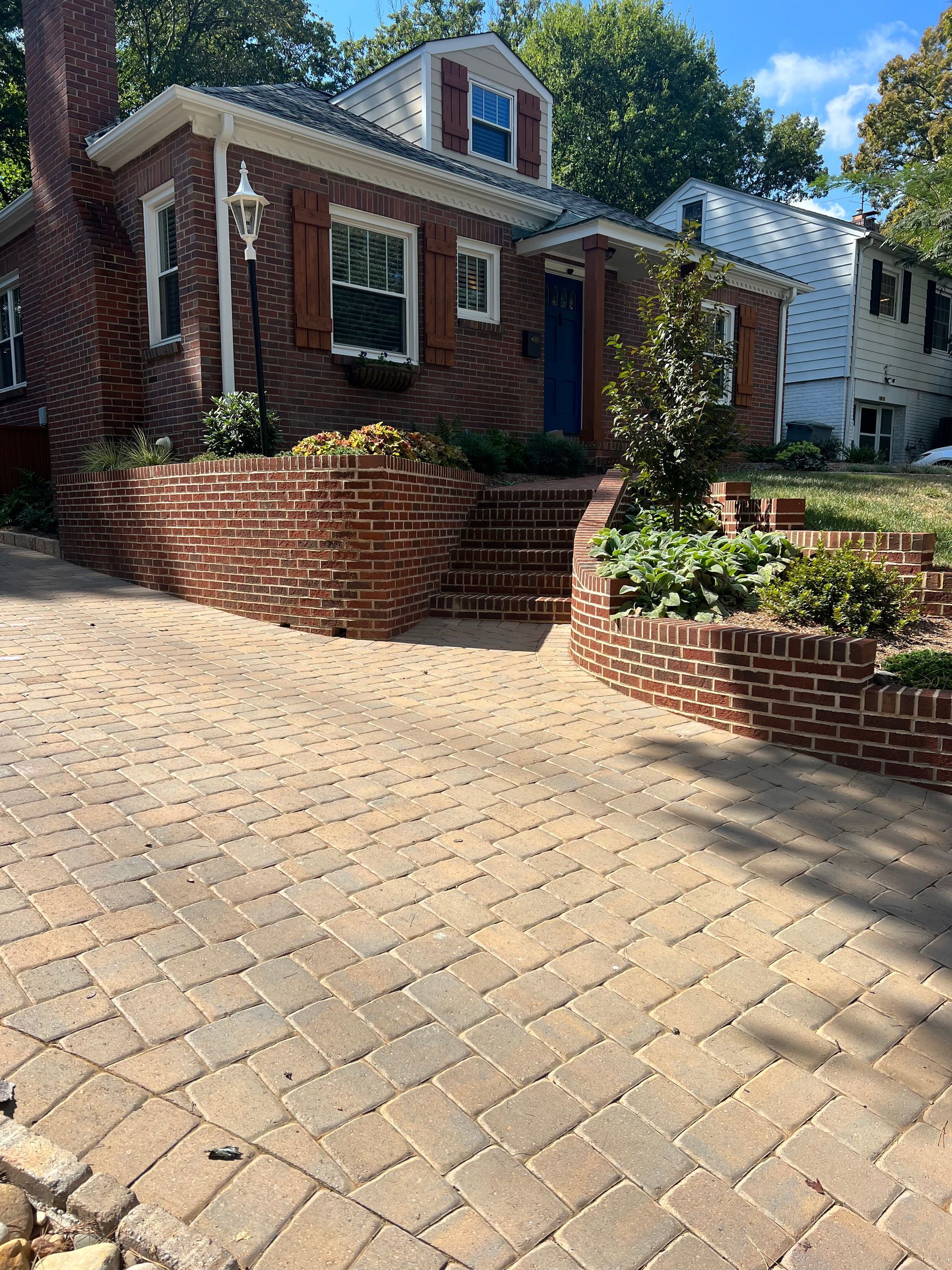A brick house with a brick driveway in front of it.