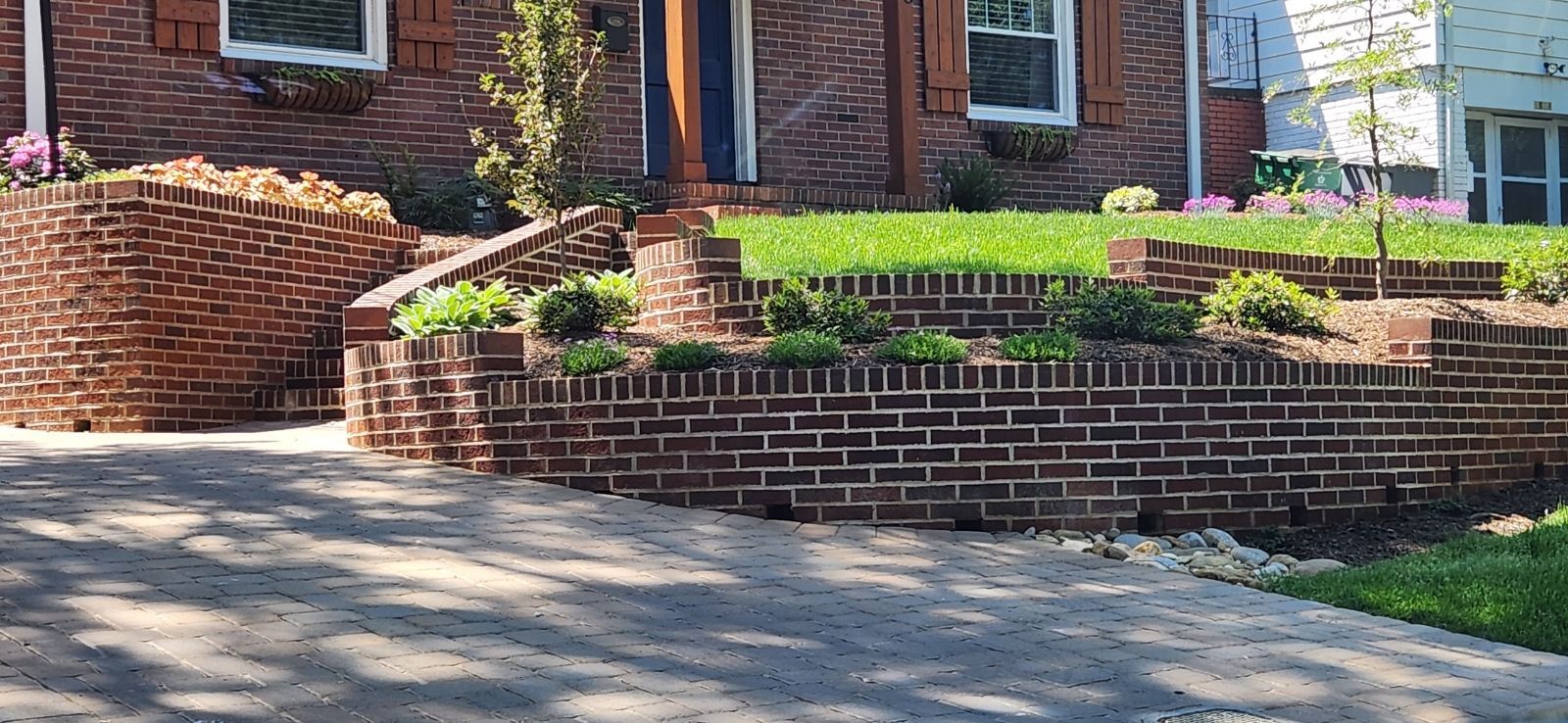 A brick wall is in front of a brick house.