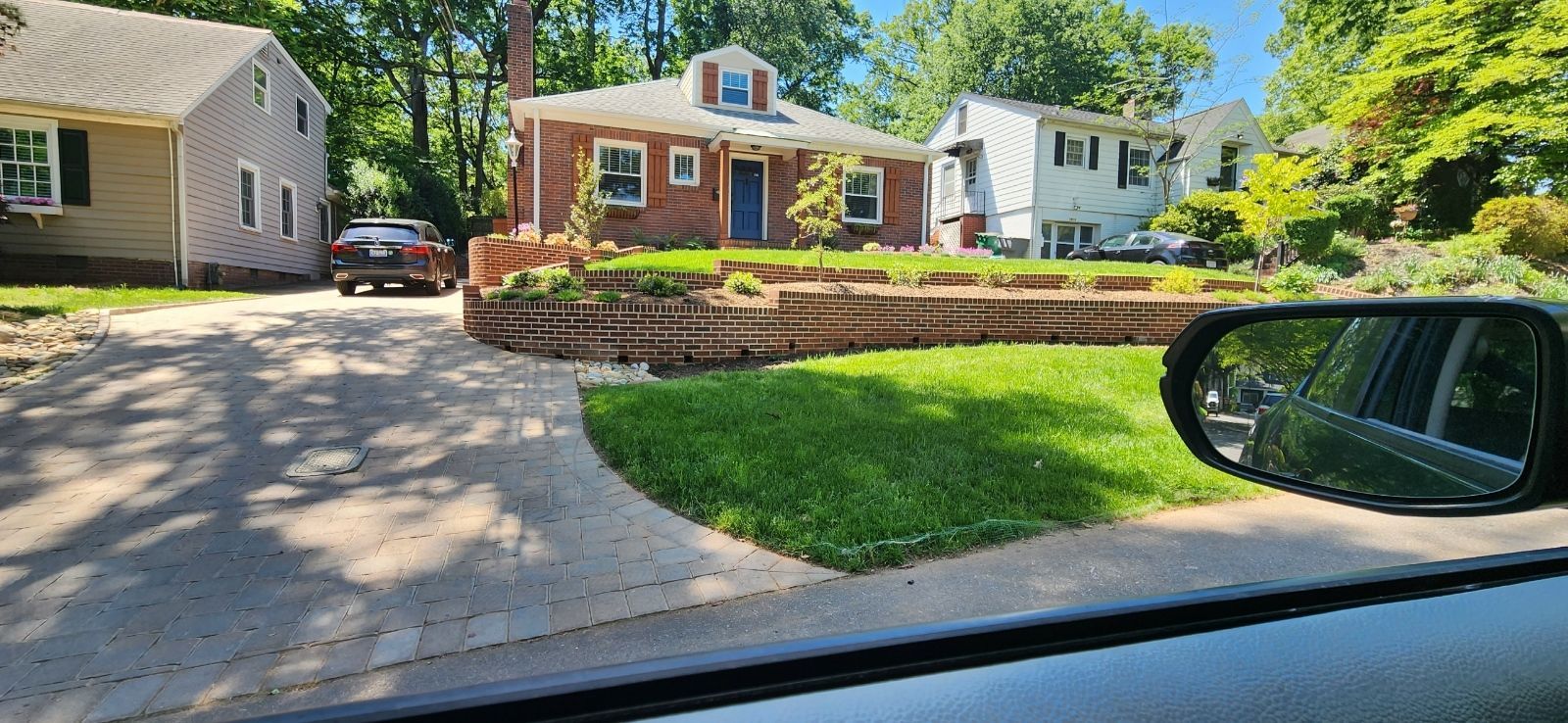 A car is parked in front of a brick house.