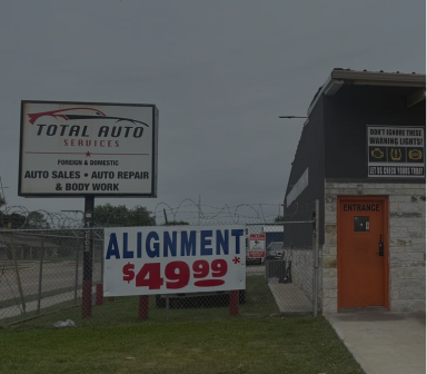Auto repair shop signs advertising wheel alignment for $49.99, with a small building and orange door.
