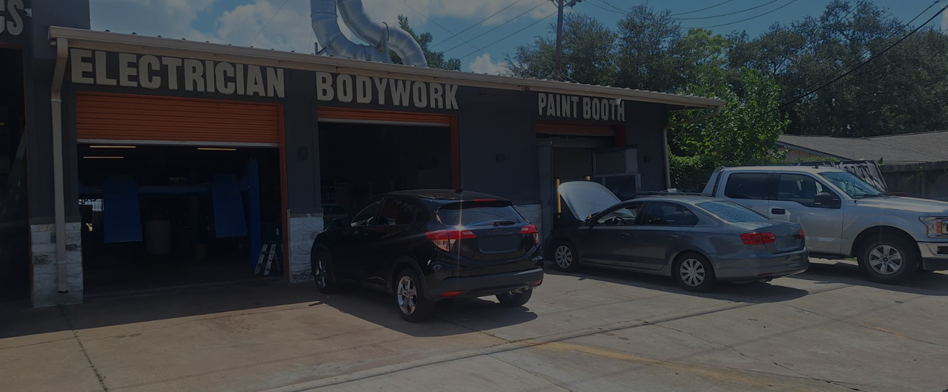Auto body shop storefront with cars parked outside under a bright blue sky | Total Auto Services
