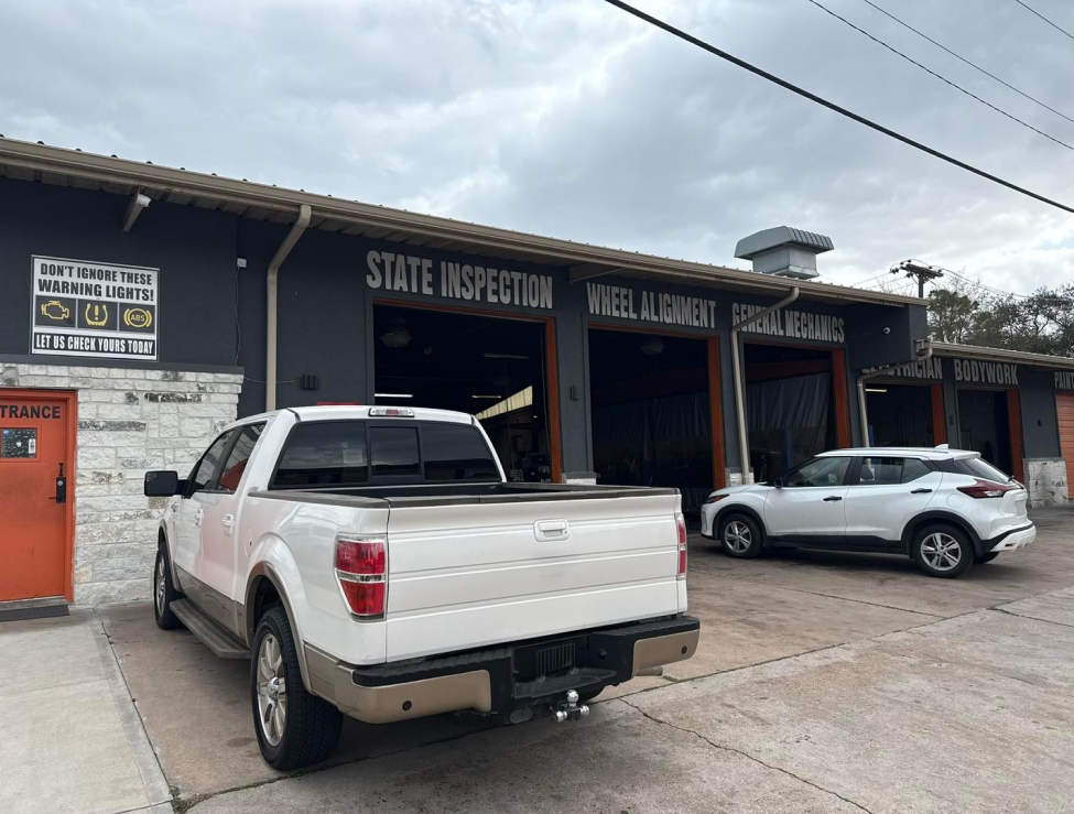 White pickup and silver SUV parked outside a State Inspection/Vehicle Inspection shop with open service bays | Total Auto Services