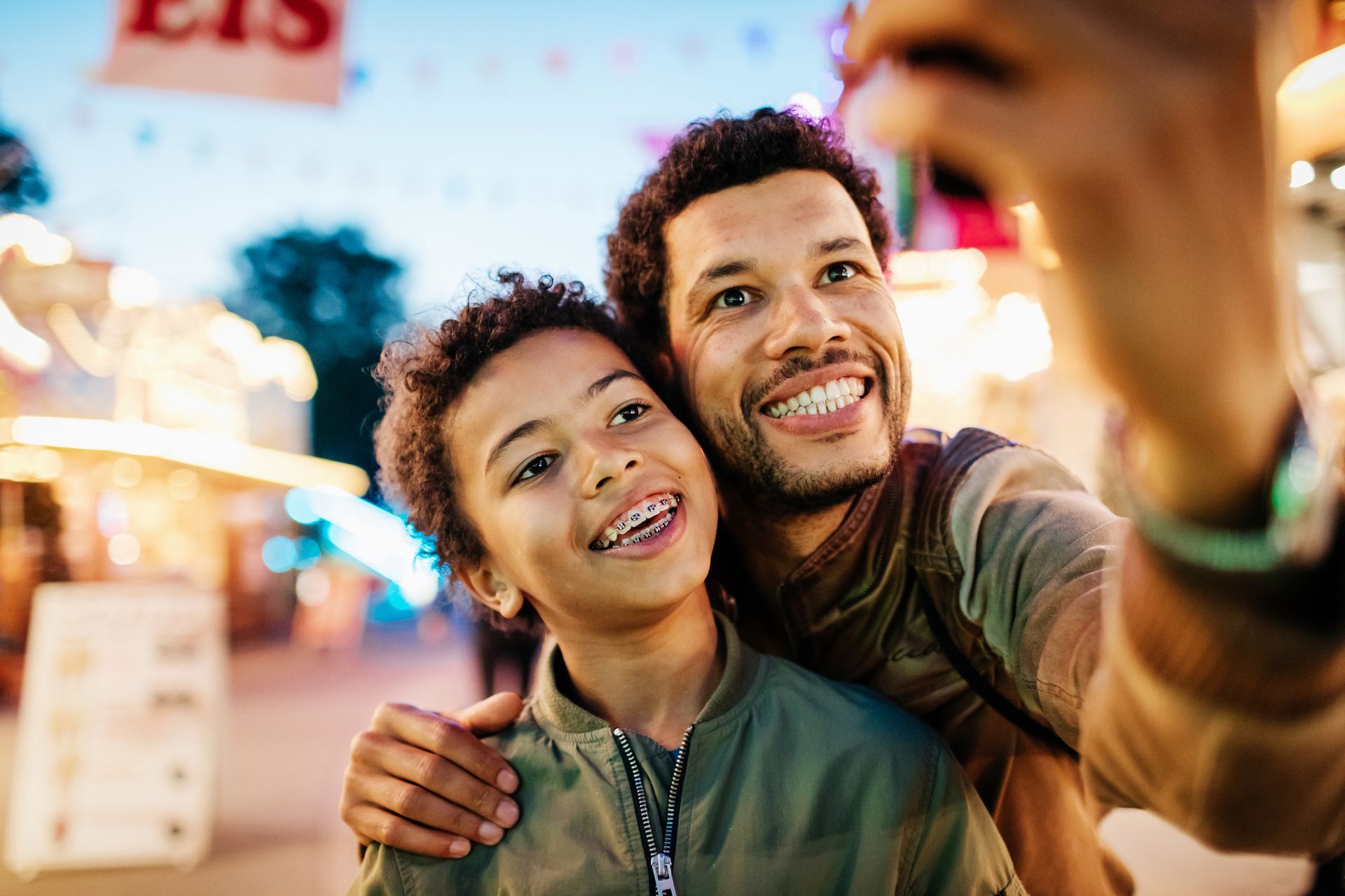 A man and a boy are taking a selfie at a carnival.