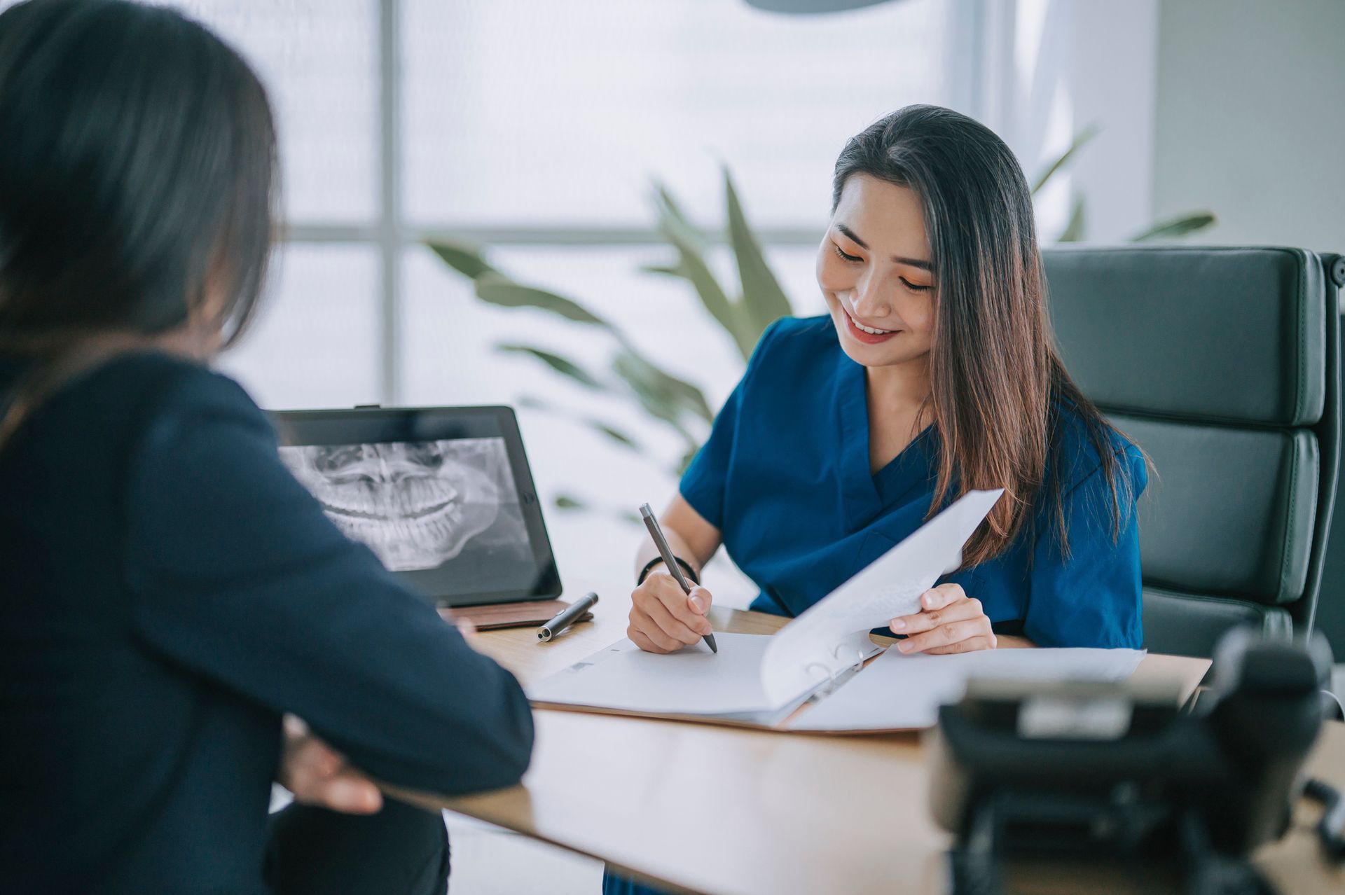 A woman is sitting at a table talking to a dentist.