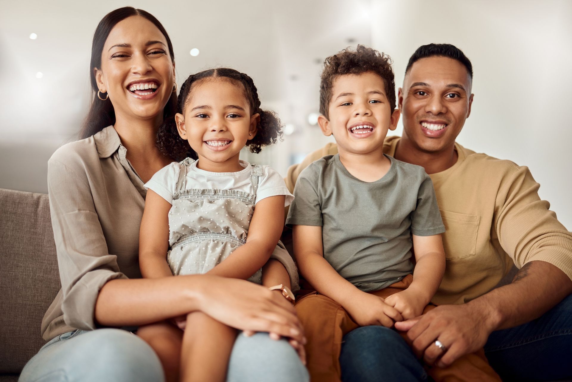 A family is sitting on a couch and smiling for the camera.