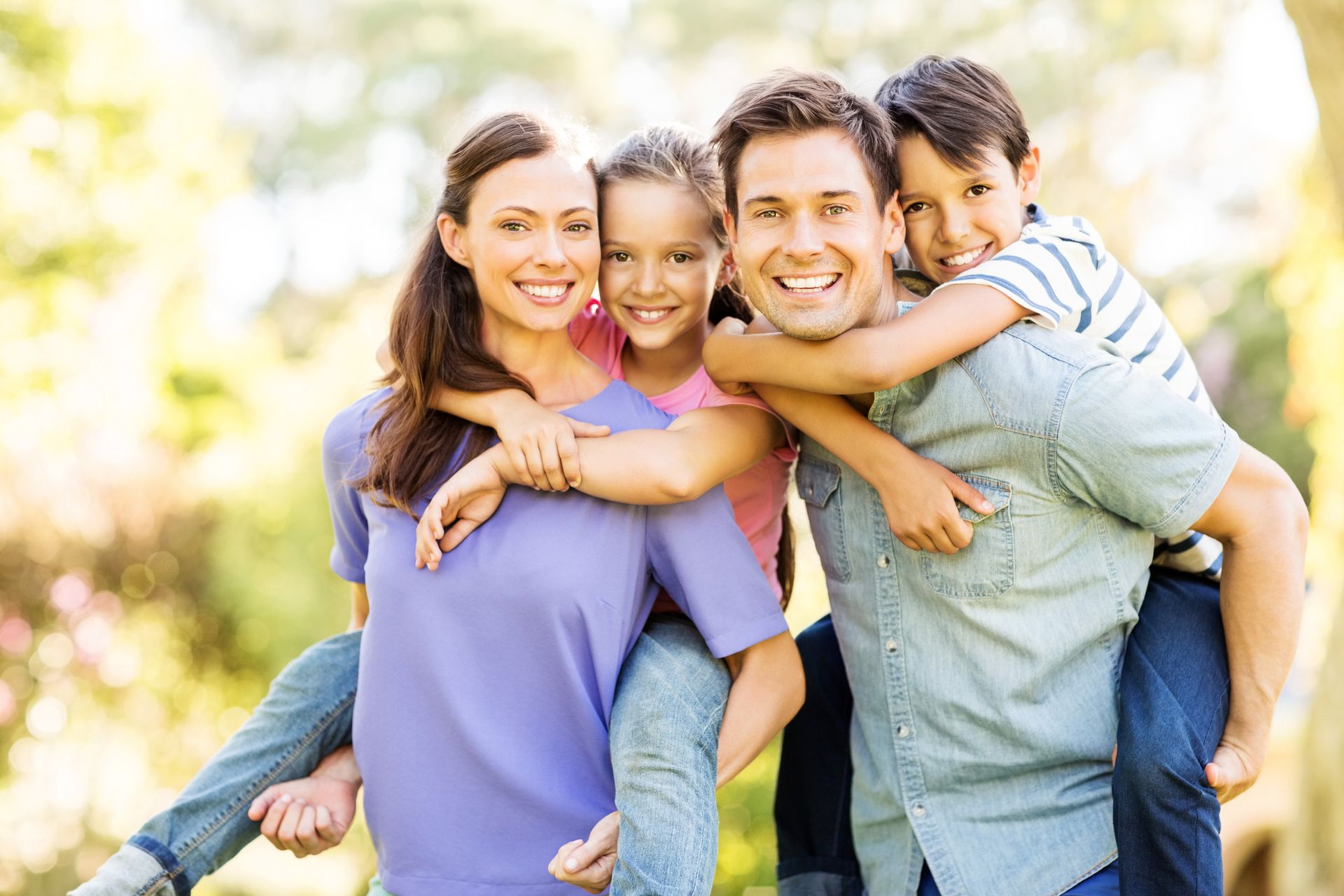 A family is posing for a picture while a man is carrying a child on his back.
