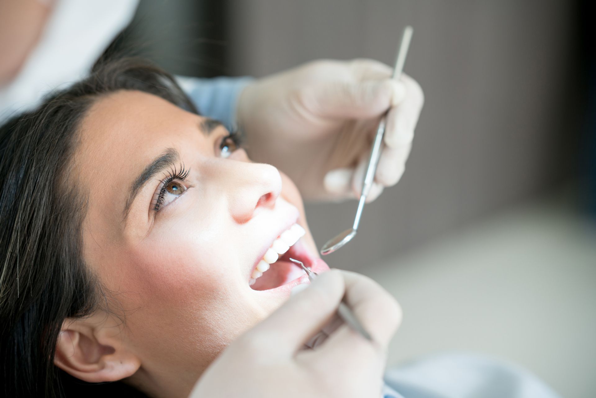 A woman is getting her teeth examined by a dentist.