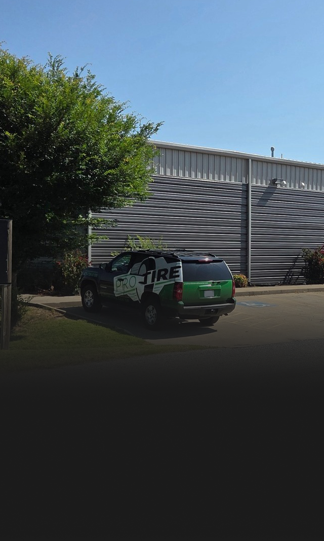 Black and green truck parked outside a building with corrugated metal siding. | Pro Tire & Automotive Center