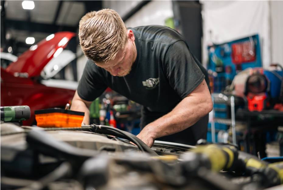 Mechanic working on a car engine in a garage. | Pro Tire & Automotive Center