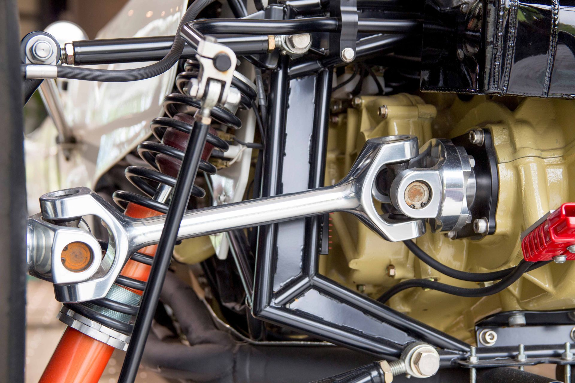 Close-up of vehicle suspension system with shock absorber and mounted wrench on frame.
