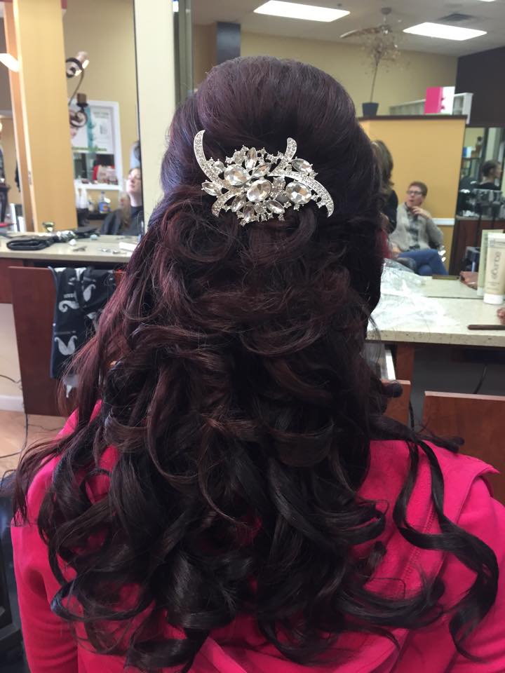 A woman in a pink shirt has her hair in a half up half down hairstyle