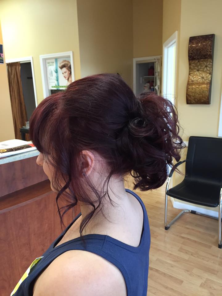 A woman is standing in a room with her hair in a bun.