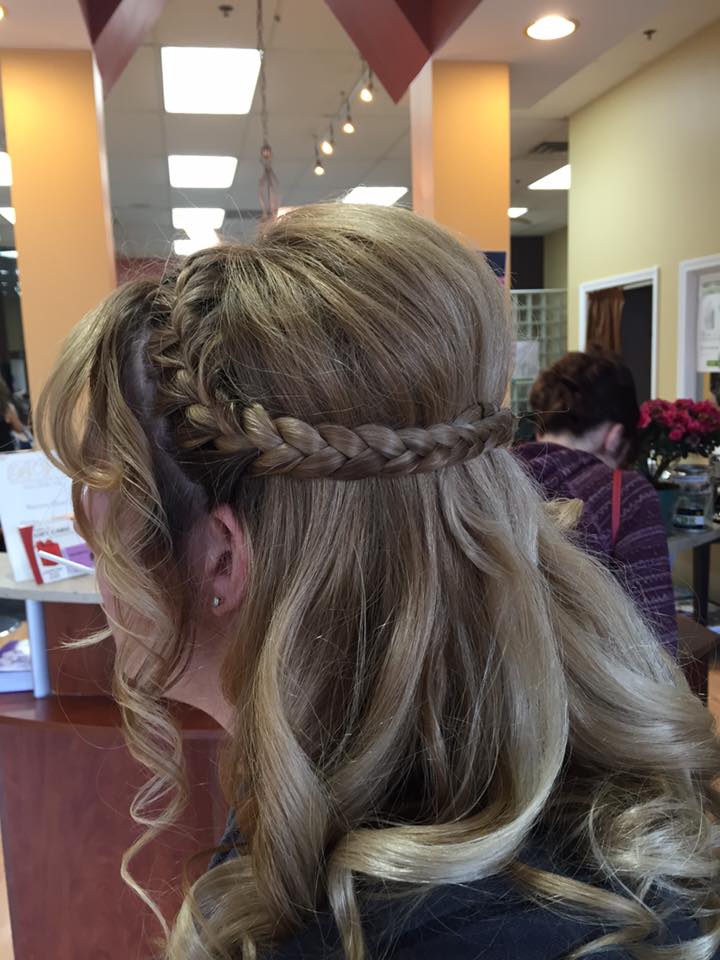 A woman is getting her hair done in a salon and has a braid in her hair.