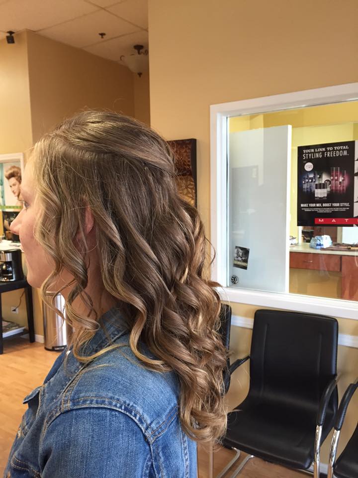 A woman is sitting in a waiting room with her hair in a half up half down hairstyle.