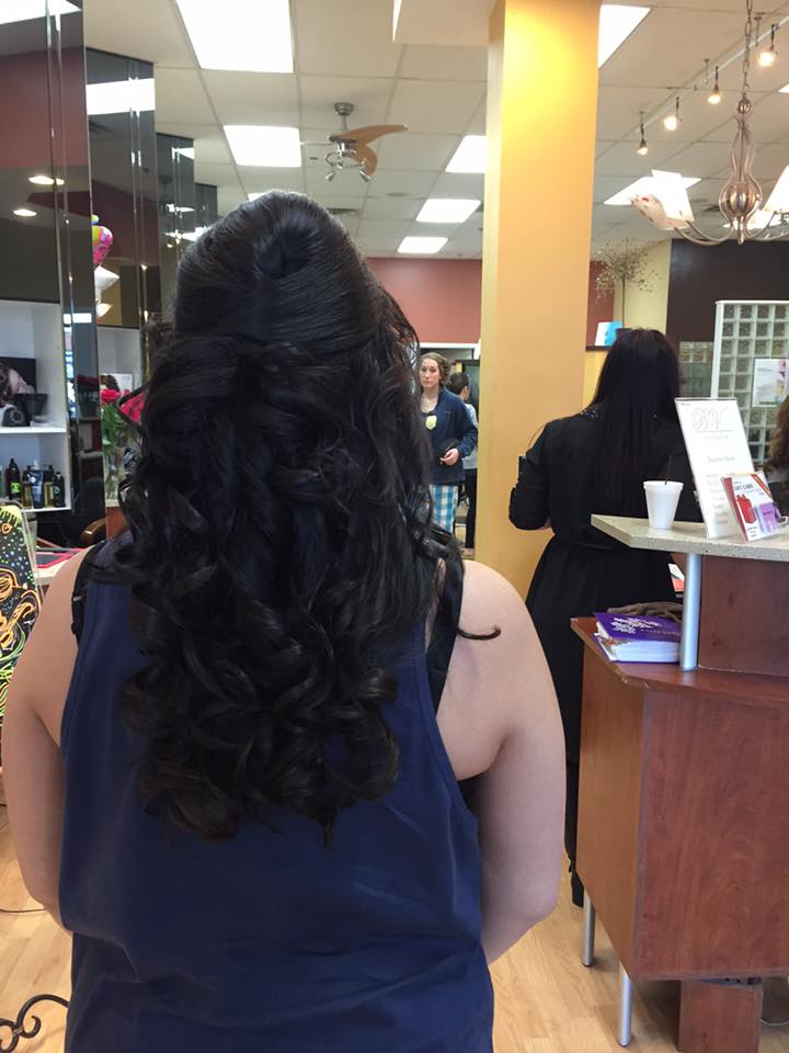 A woman in a blue tank top is standing in a salon