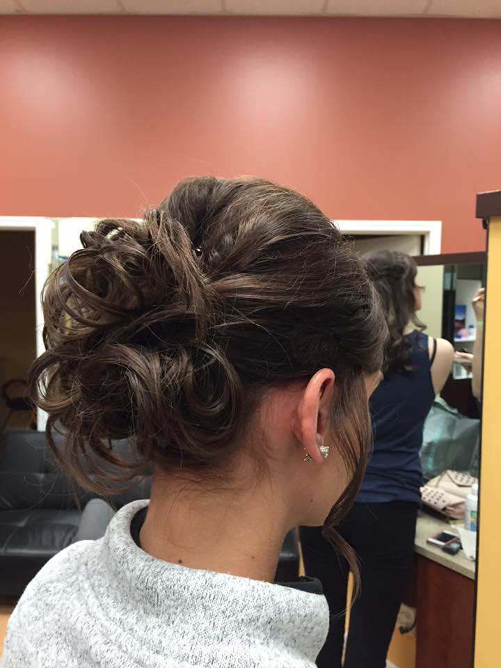A woman with her hair in a bun is standing in front of a mirror.