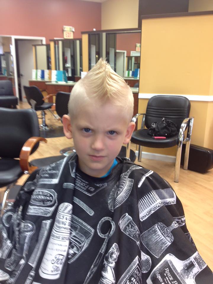 A young boy is getting his hair cut at a barber shop