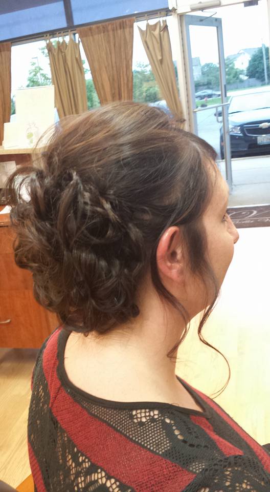 A woman is sitting in a chair with her hair in a bun.