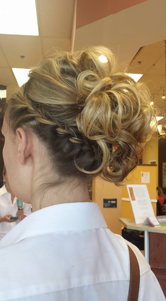 A woman is wearing a white shirt and has her hair in a bun.