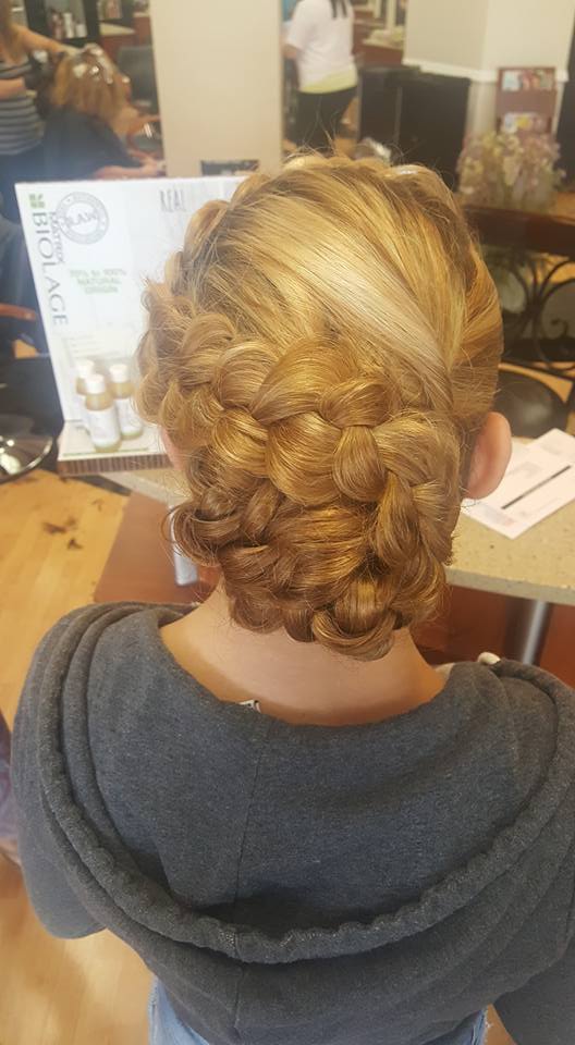 A woman is getting her hair braided in a salon.