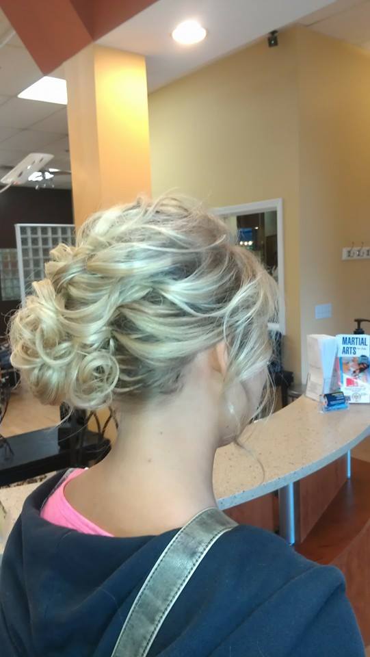 A woman with blonde hair in a bun is standing in a salon.
