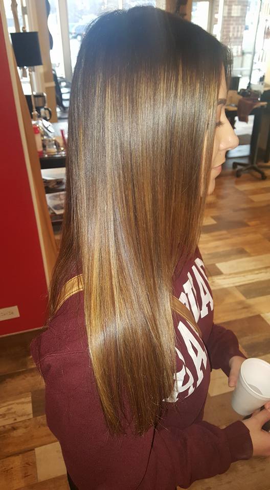 A woman with long hair is sitting at a table holding a cup of coffee.
