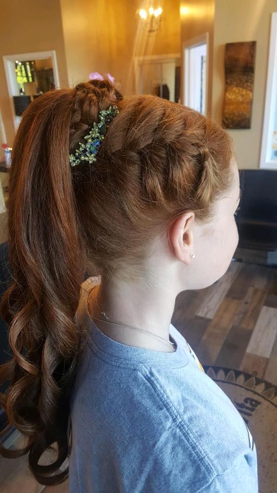 A little girl with red hair is wearing a braided ponytail.