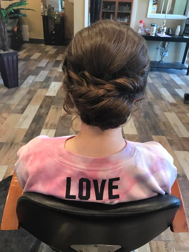 A woman is sitting in a chair with her hair in a bun.