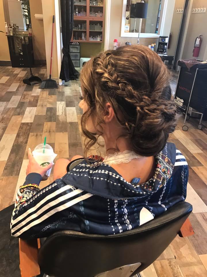 A woman is sitting in a chair with her hair in a bun.