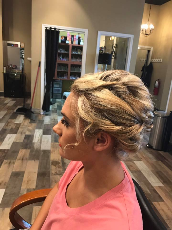 A woman is sitting in a chair with her hair in a bun.