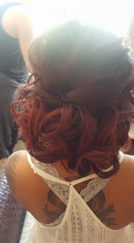 A woman with red hair is wearing a white dress and has a tattoo on her back.