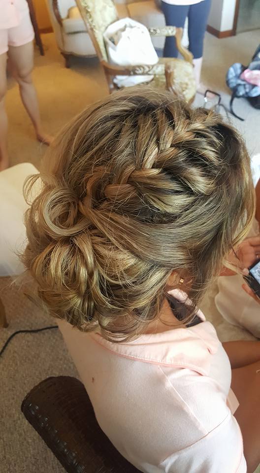 A woman is sitting in a chair with her hair in a bun.
