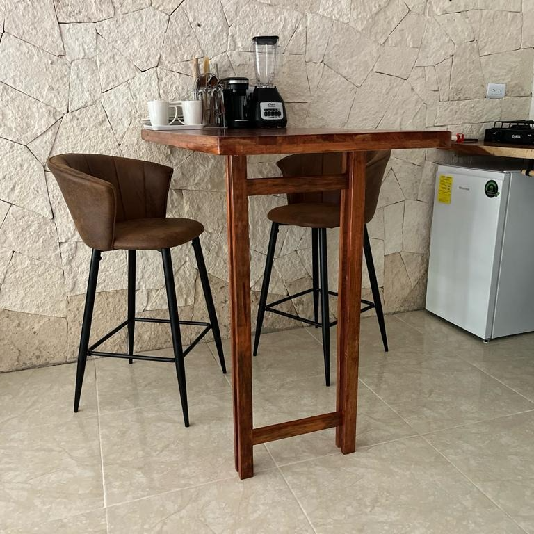 A wooden table with two chairs and a blender on it in a kitchen.