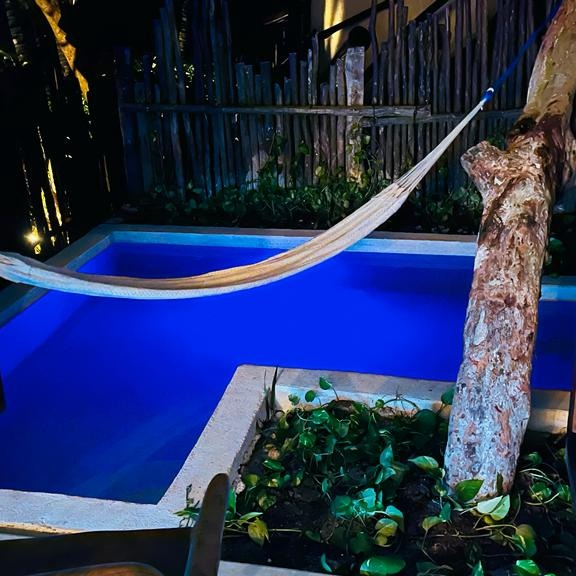 A hammock is hanging over a swimming pool at night